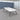 White rounded rectangular meeting table with a black edge, splayed black legs and two cable ports in the office, full room view